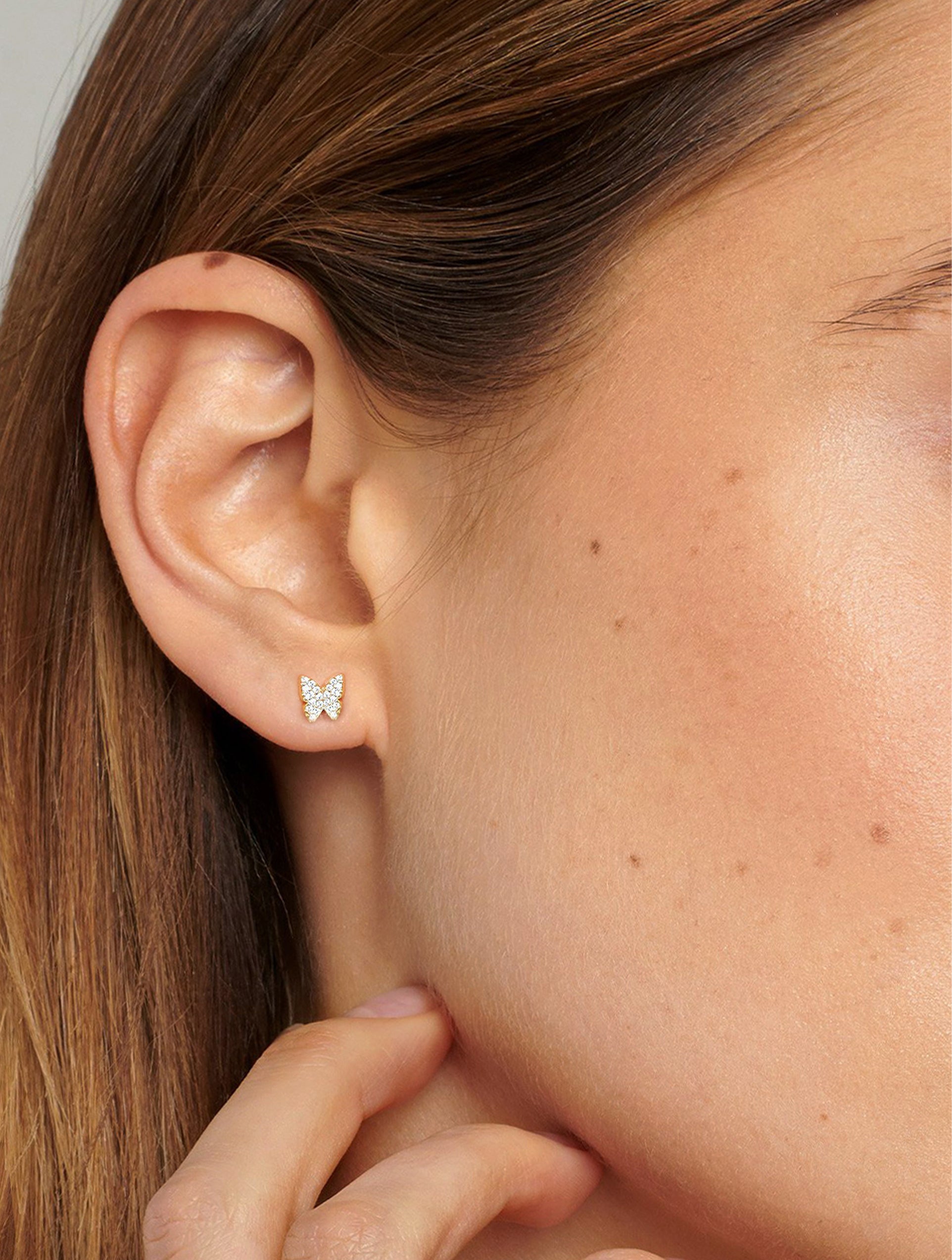 Gold butterfly stud earrings with small, sparkling cubic zirconia stones that simulate a diamond.