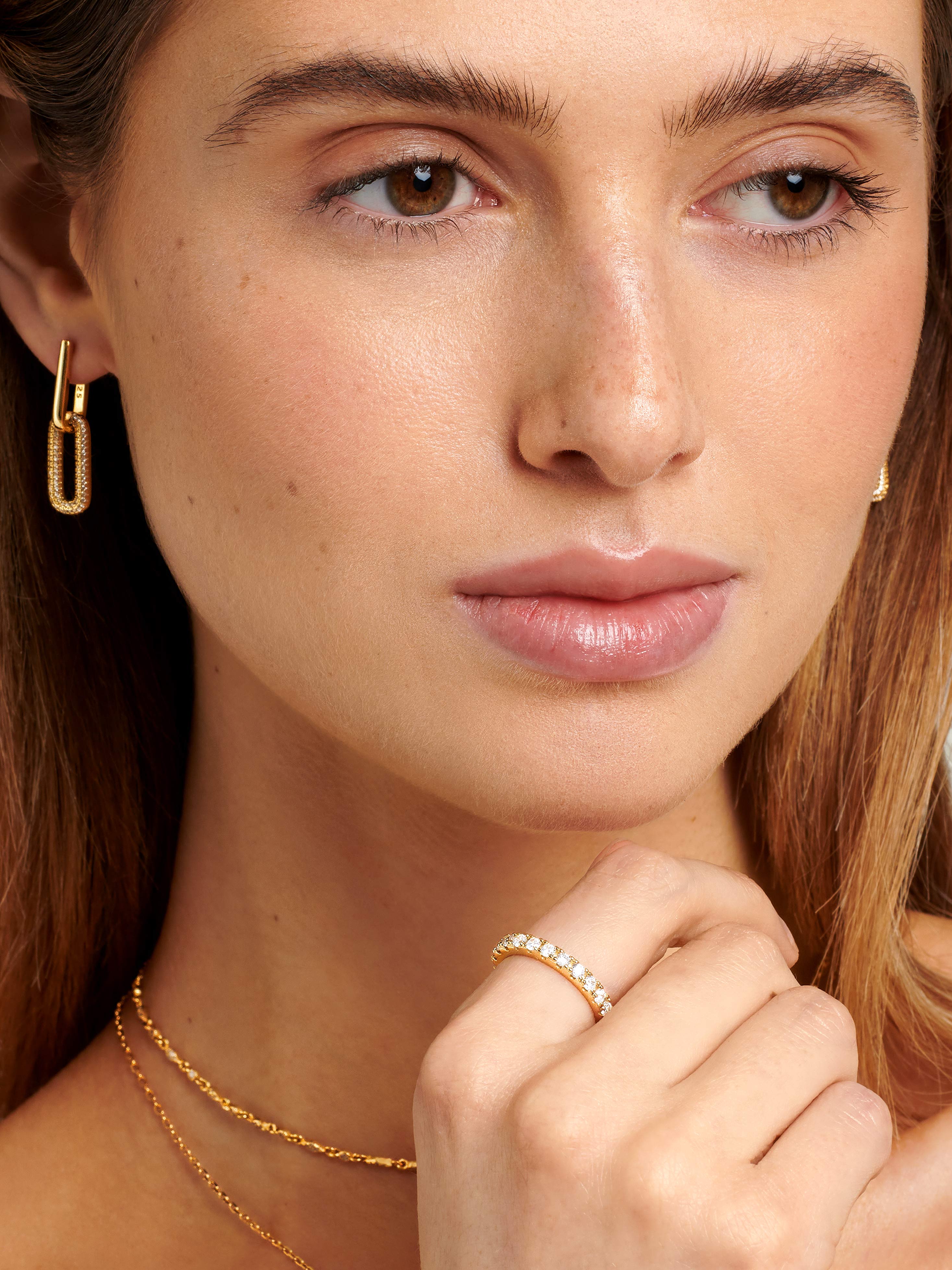 Female model wearing gold Eternity Ring With Sparkly Stones styled together with chain hoop earrings.