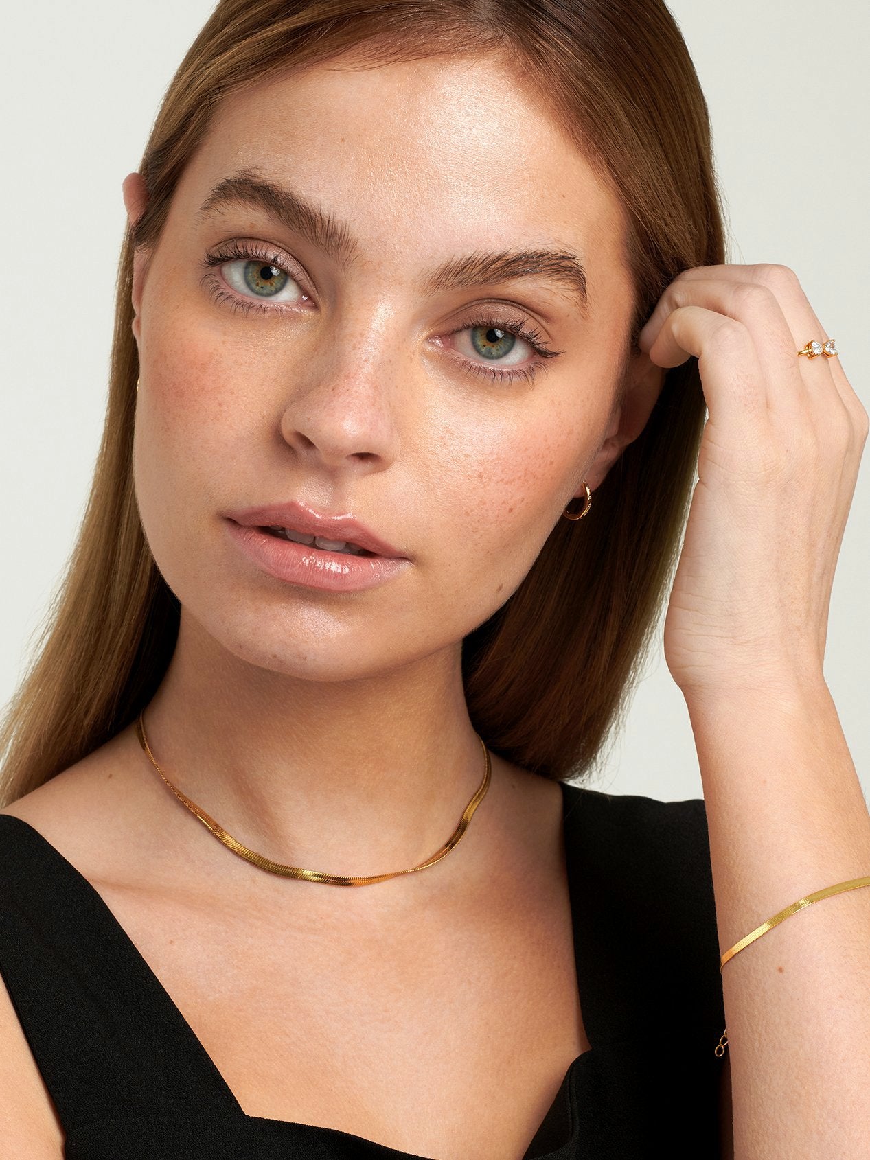 Model wearing gold herringbone necklace with the matching bracelet.