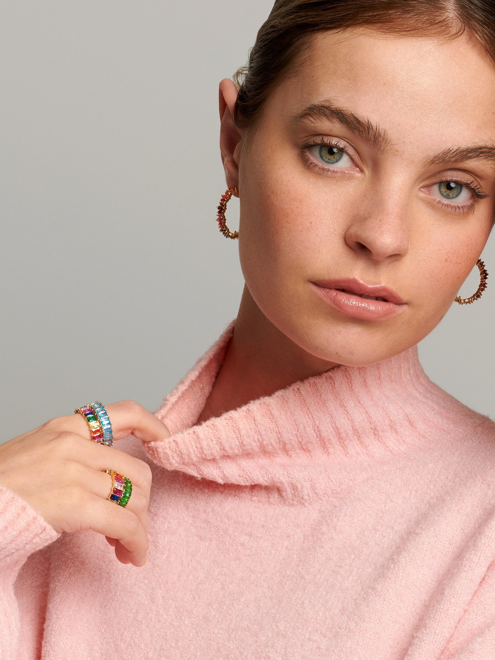 Teenage model wearing y2k inspired rings with colourful stones in turquoise, rainbow and green.
