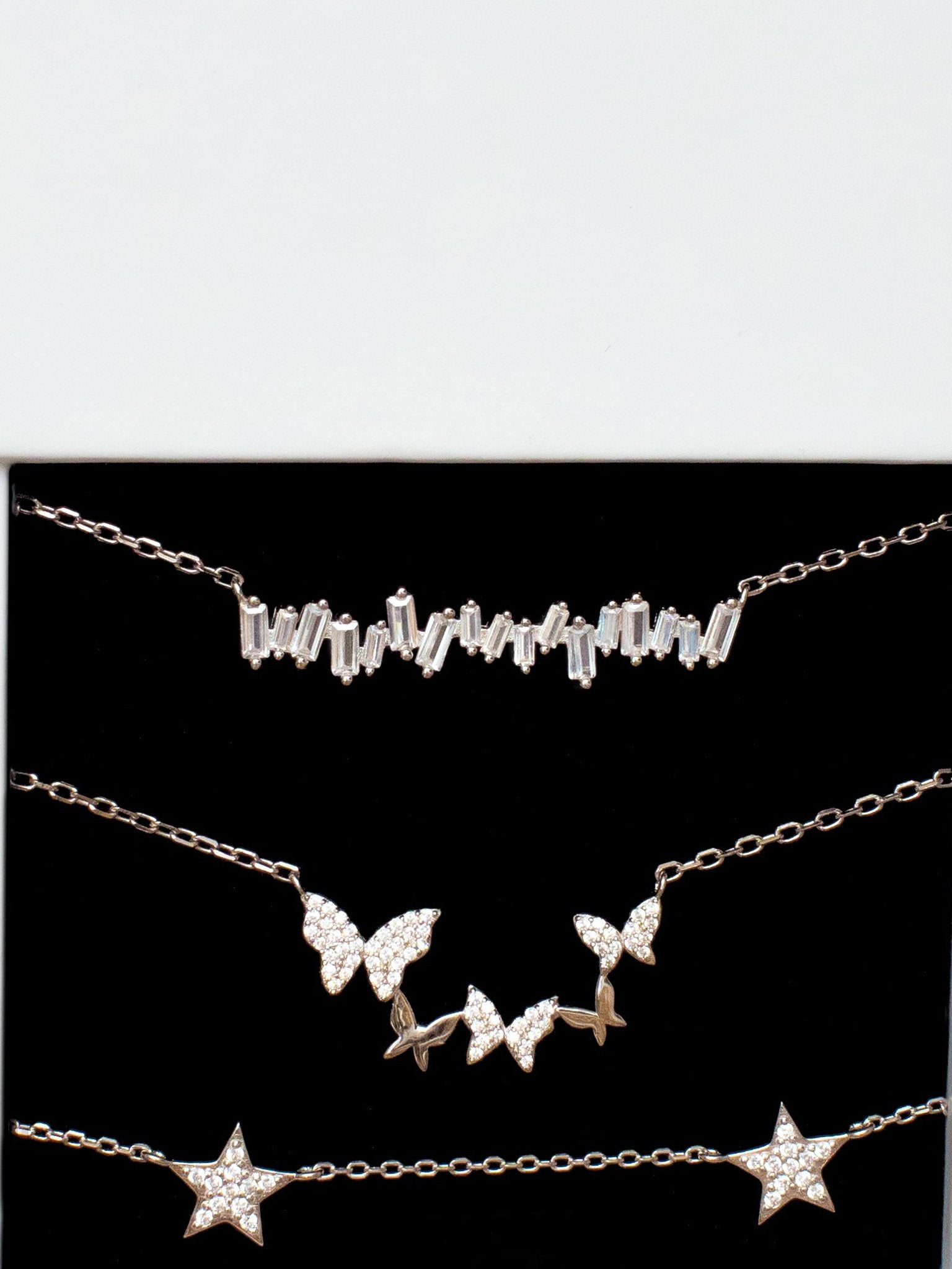 Sterling silver butterfly necklace layered with two other necklaces inside a white gift box.