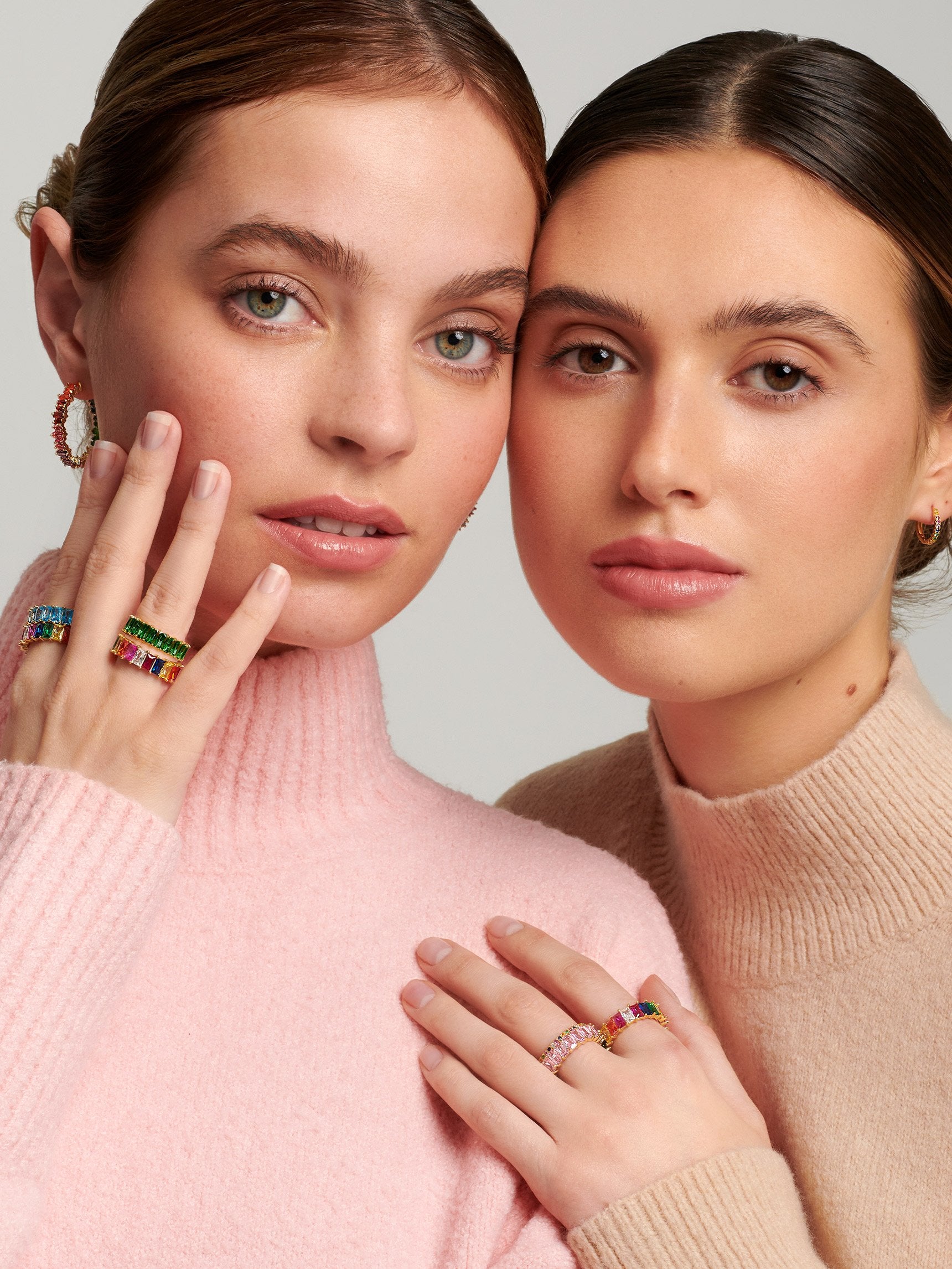 Two models wearing rainbow jewellery.