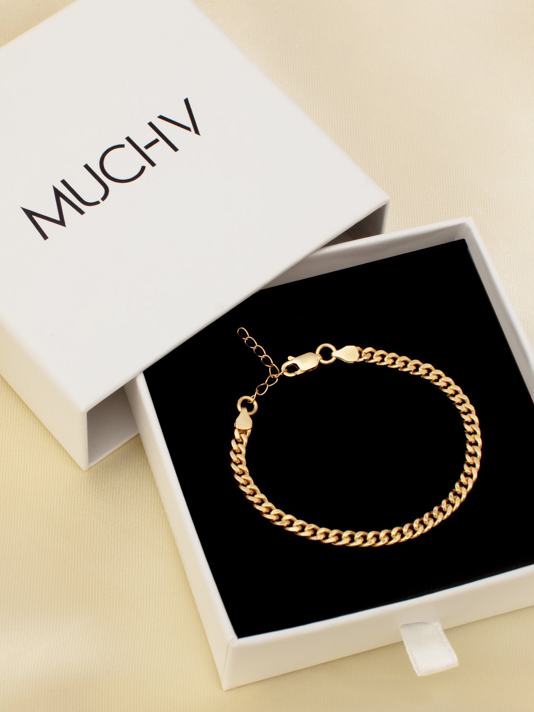 Gold curb chain bracelet with an adjustable chain extender inside a white gift box.
