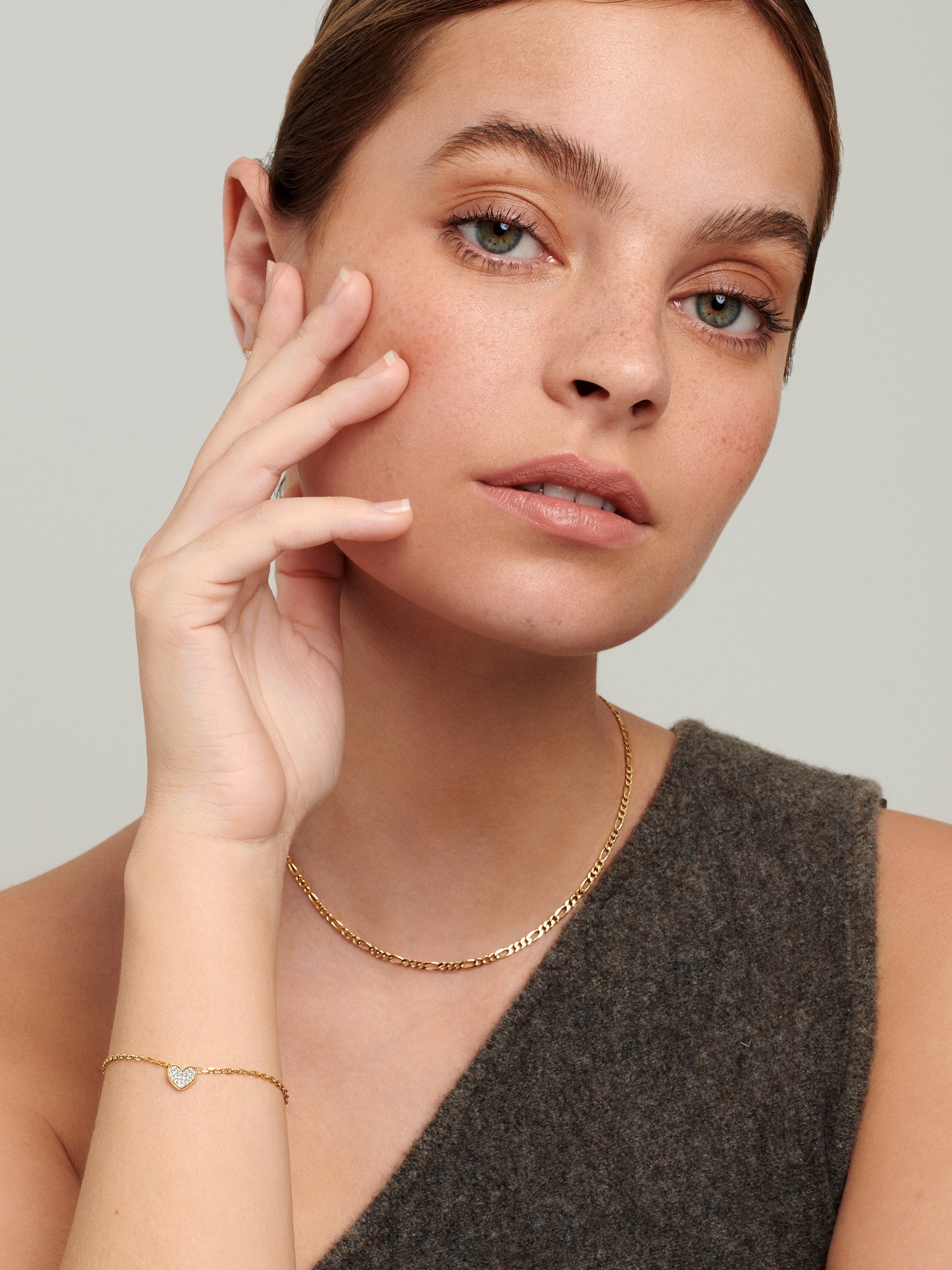 Female model wearing gold heart bracelet .