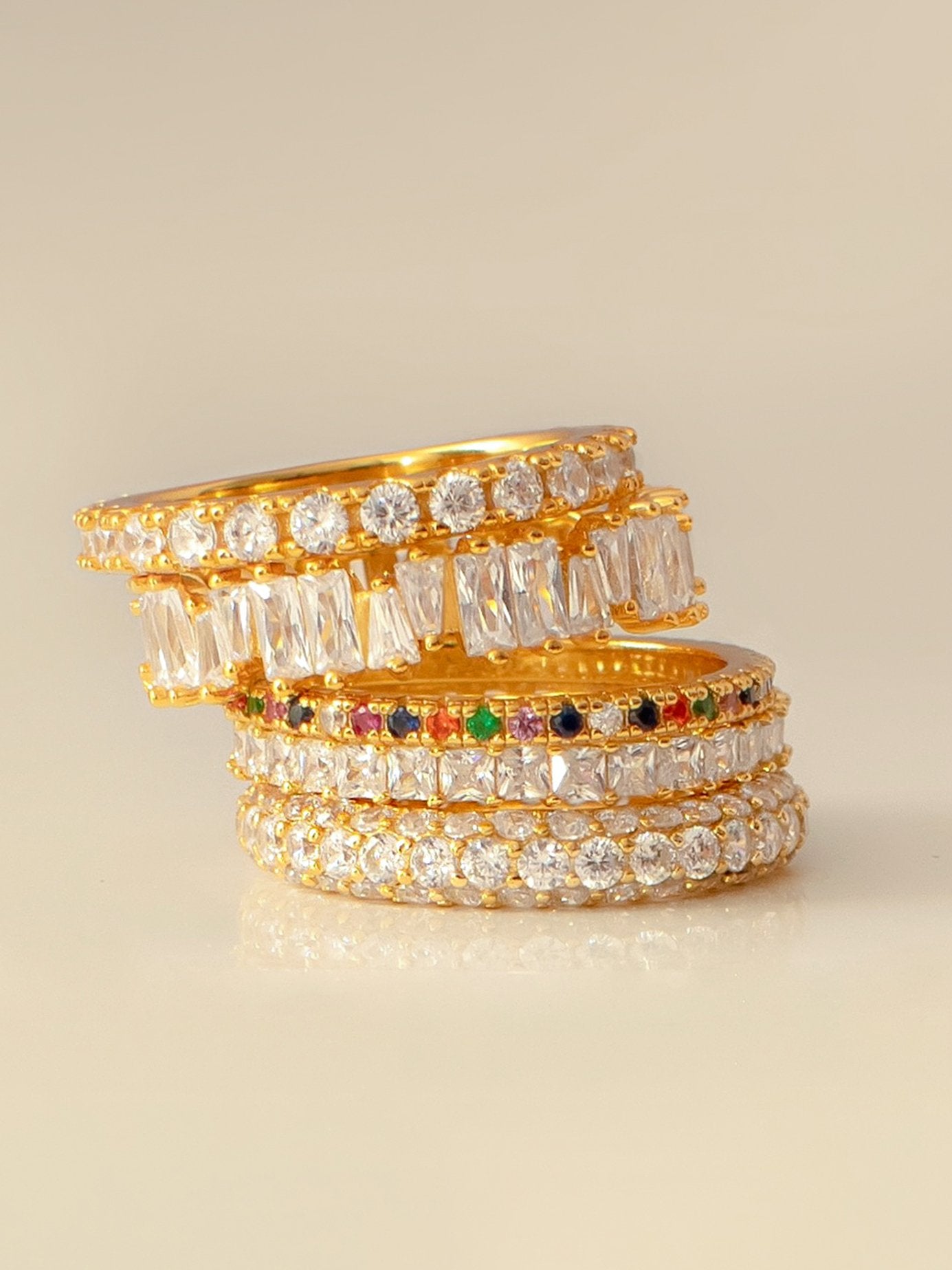 Gold stacking ring with baguette stones stacked with other gold eternity rings for women.
