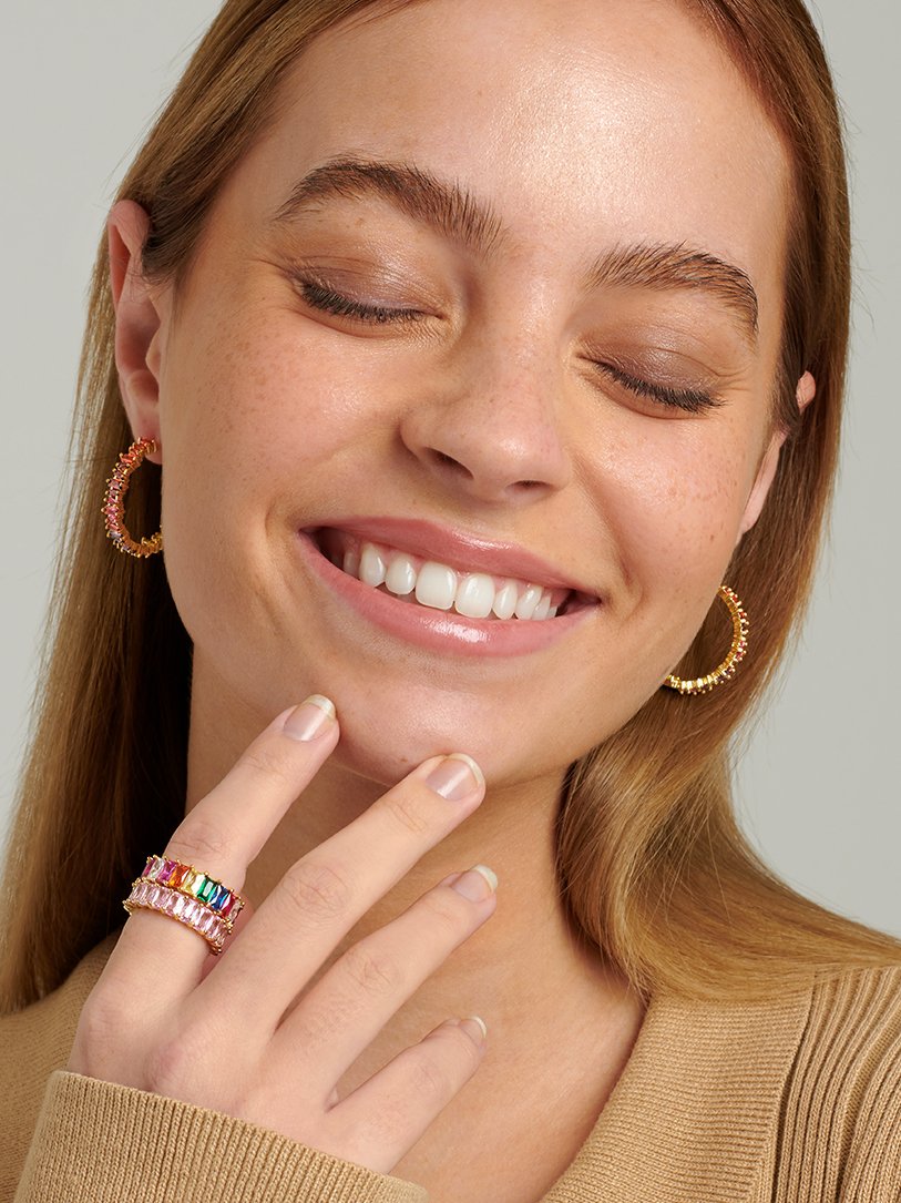 Model wearing gold rainbow hoop earrings.