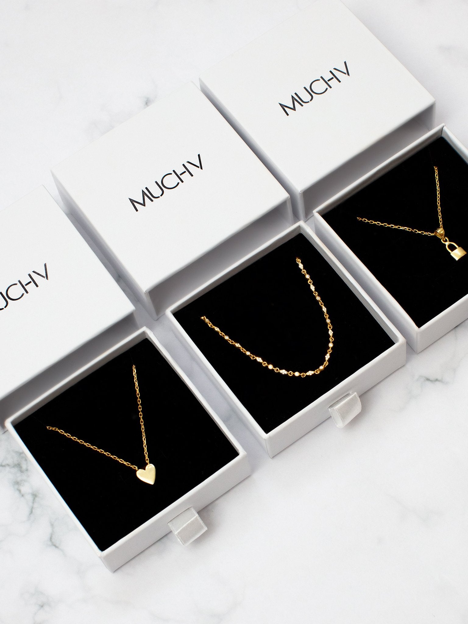Gold pendant necklaces for women in white gift boxes.