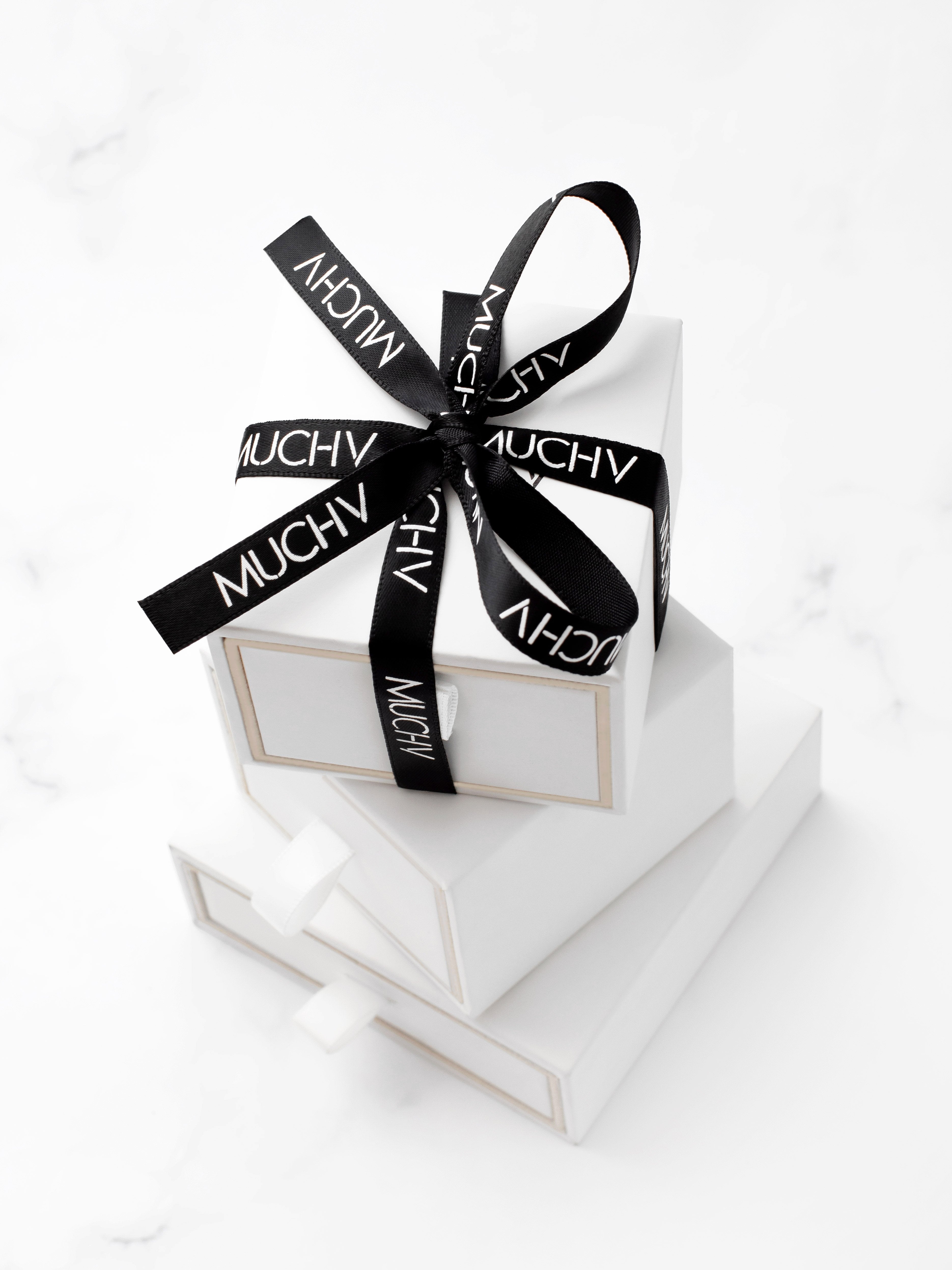 White ring box with a black ribbon.