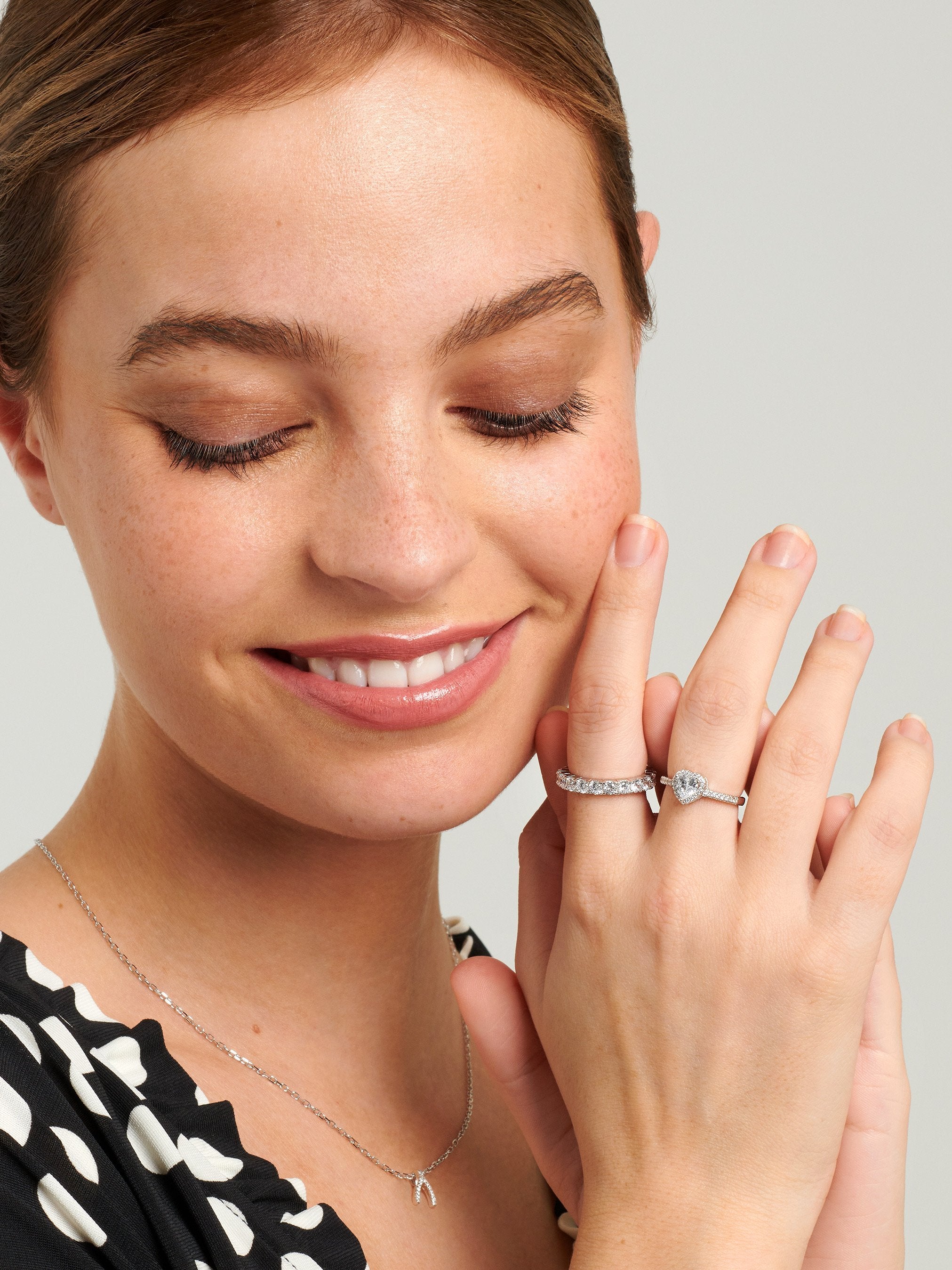 Female wearing sterling silver heart ring with a silver eternity band.