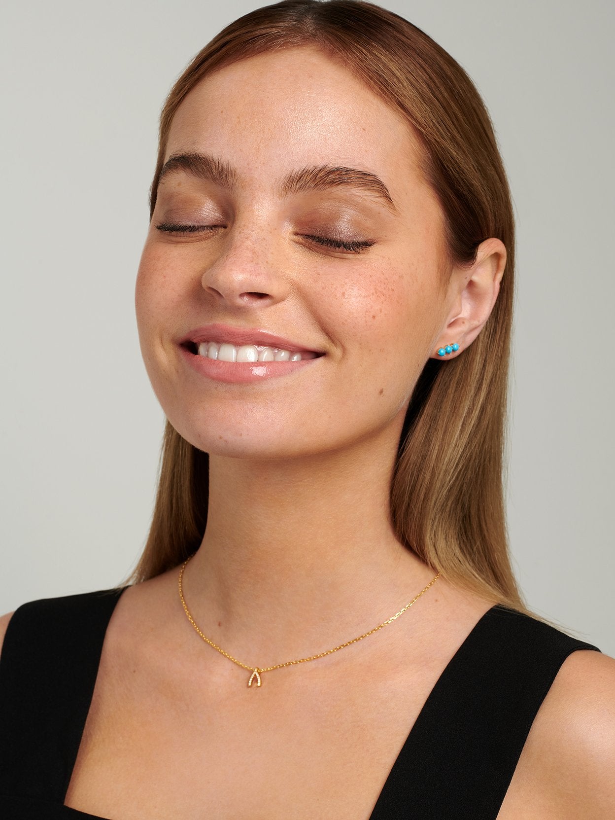 Teenage model wearing a gold necklace with a small wishbone pendant.